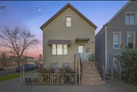 a two story home with stairs leading up to the front door